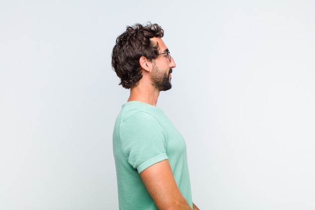 Young bearded man on profile view looking to copy space ahead, thinking, imagining or daydreaming