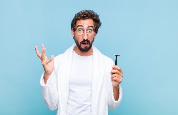 Young bearded man screaming with hands up in the air, feeling furious, frustrated, stressed and upset