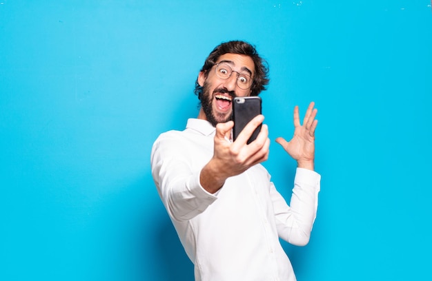 Молодой бородатый мужчина показывает экран своего мобильного телефона