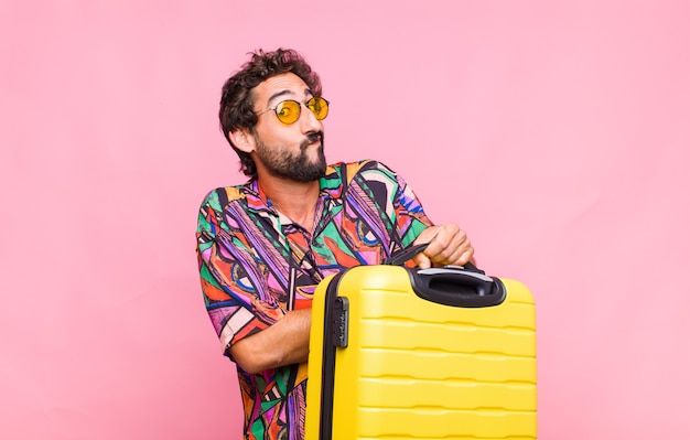 Young bearded man shrugging, feeling confused and uncertain, doubting with arms crossed and puzzled look