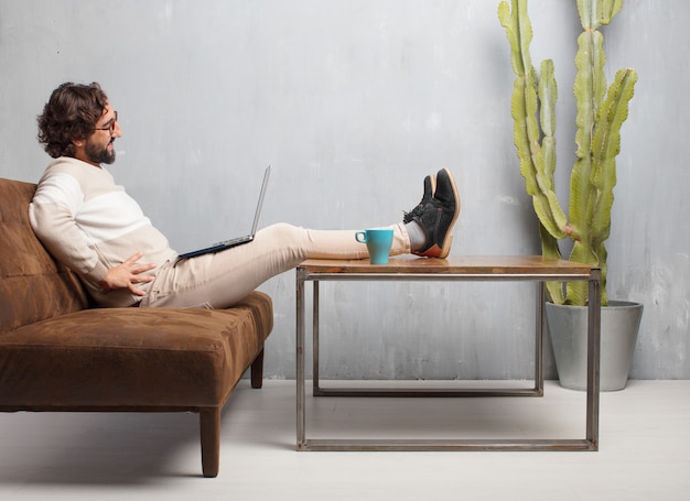 Young bearded man sitting on a leather sofa in a vintage living room