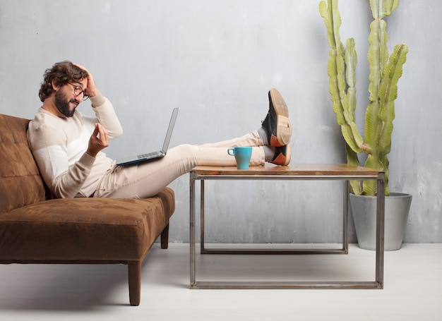 Young bearded man sitting on a leather sofa in a vintage living room