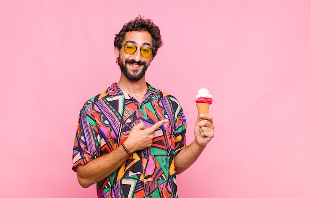 Young bearded man smiling cheerfully, feeling happy and pointing to the side and upwards, showing object in copy space