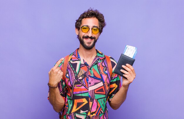 Young bearded man smiling confidently pointing to own broad smile, positive, relaxed, satisfied attitude