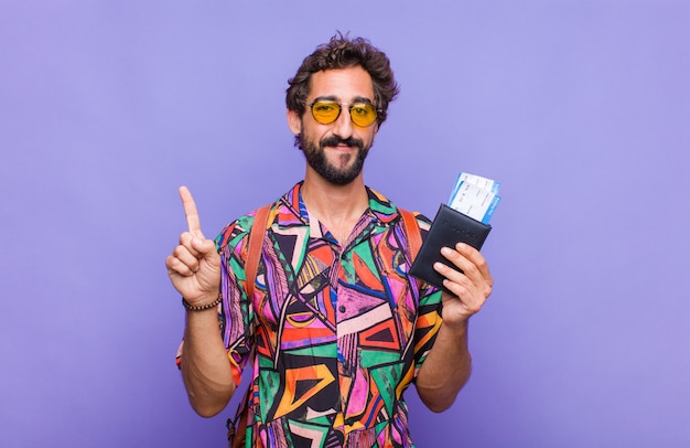 Young bearded man smiling and looking friendly, showing number one or first with hand forward, counting down