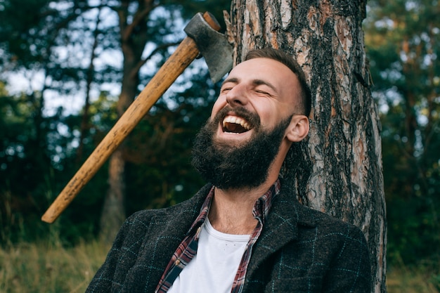 Young bearded man smiling widely in the woods outdoors. Happy man