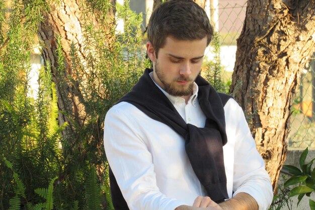 Photo young bearded man standing against trees