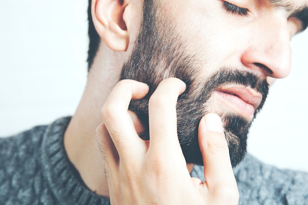 Young bearded man touching his beard while standing