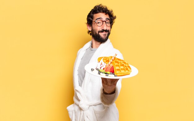 Young bearded man wearing bathrobe and having breakfast