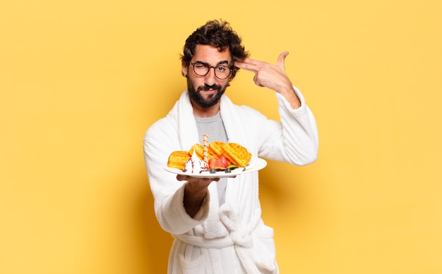 Giovane uomo barbuto che indossa accappatoio e fa colazione