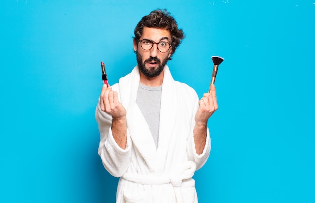 Young bearded man wearing bathrobe and make up tools