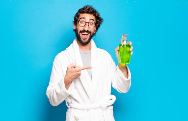 Young bearded man wearing bathrobe and shampoo