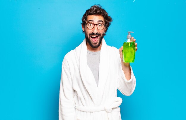 Young bearded man wearing bathrobe and shampoo