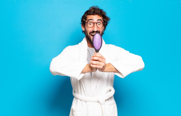 Young bearded man wearing bathrobe with a hairbrush