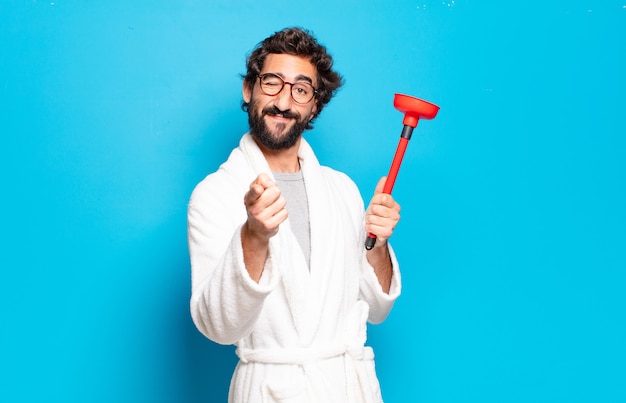 Young bearded man wearing bathrobe with a plunger