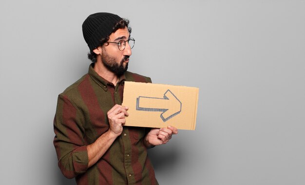 Young bearded man with an arrow symbol on cardboard