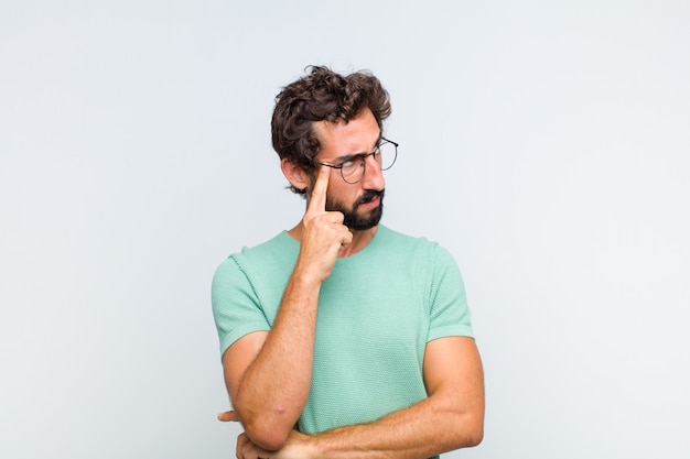 Young bearded man with a concentrated look, wondering with a doubtful expression, looking up and to the side