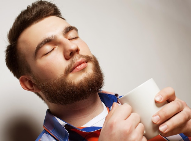 커피 한 잔 을 들고 있는 수염 을 가진 젊은 남자
