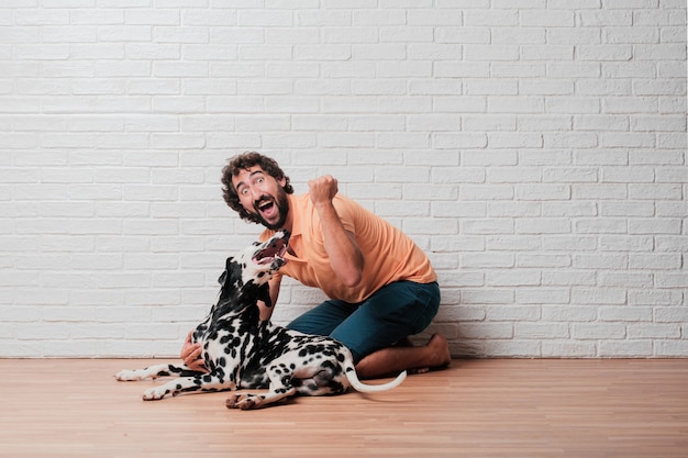 Young bearded man with a dalmatian dog against white brick wall 