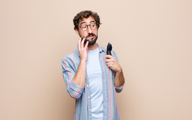 Young bearded man with a electric razor