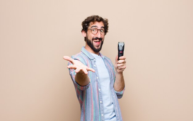 Young bearded man with a electric razor