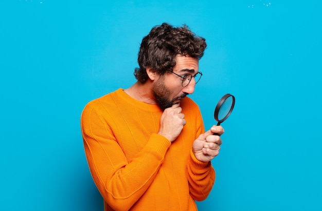 Young bearded man with a magnifying glass