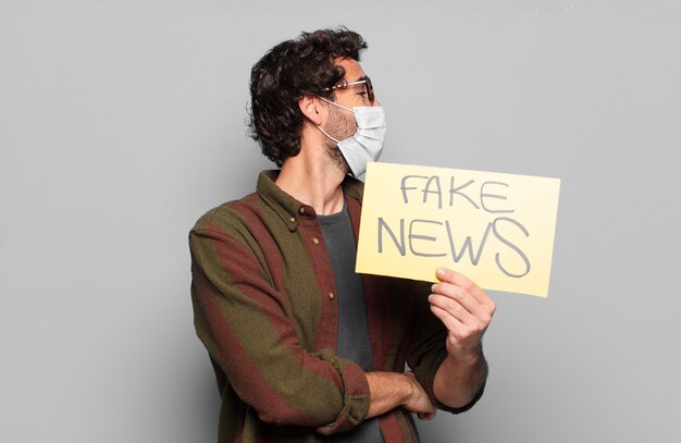 Photo young bearded man with a medical mask and fake news