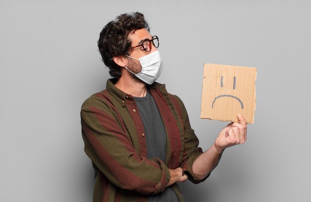 young bearded man with a medical mask and sad banner concept