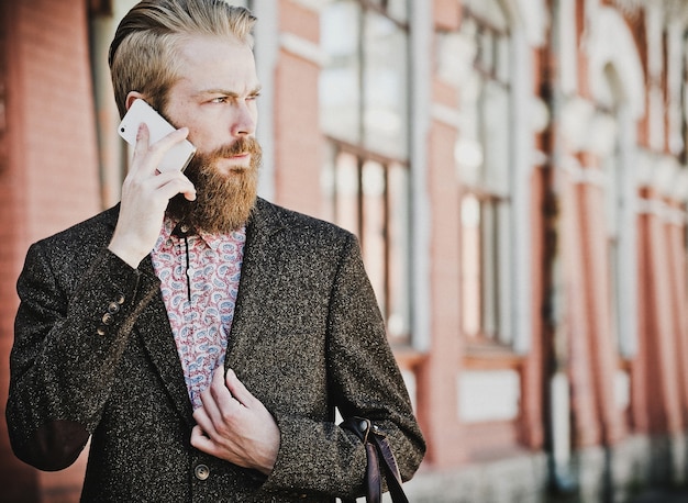 Young bearded man with mobile, outdoor, summer time