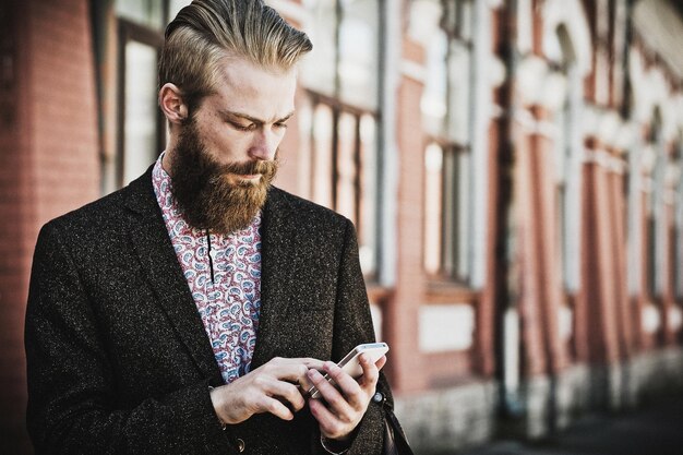 Young bearded man with mobile outdoor summer time