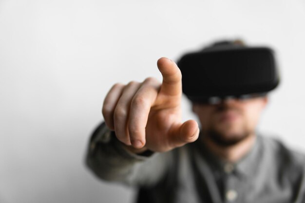 Young bearded man with virtual reality glasses trying to touch something