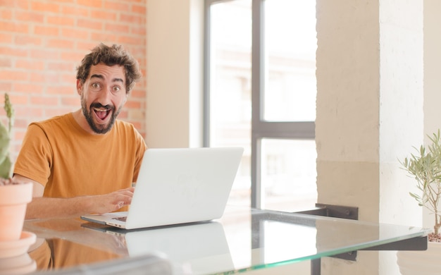 Giovane uomo barbuto che lavora a casa con un computer portatile