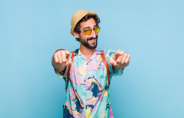 Young bearded tourist man feeling happy and confident, pointing to camera with both hands and laughing, choosing you