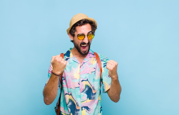 Young bearded tourist man feeling happy, surprised and proud