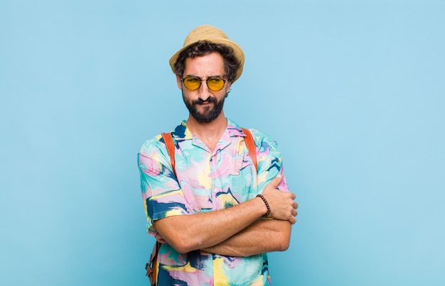 Young bearded tourist man feeling sad, upset or angry and looking to the side with a negative attitude, frowning in disagreement