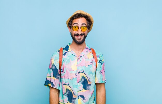 Young bearded tourist man looking happy and goofy with a broad, fun, loony smile and eyes wide open