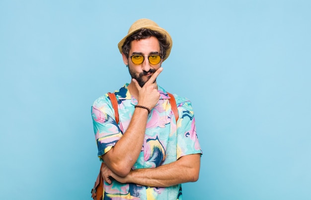 Young bearded tourist man looking serious, thoughtful and distrustful, with one arm crossed and hand on chin, weighting options