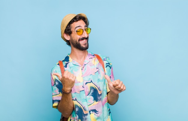 Young bearded tourist man smiling cheerfully and casually pointing