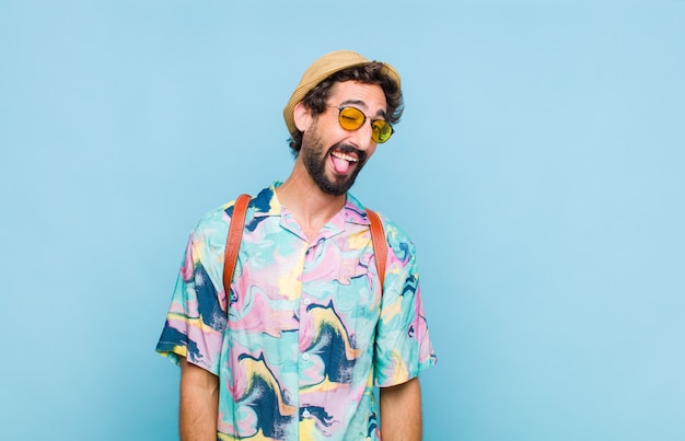 Young bearded tourist man with cheerful, carefree, rebellious attitude, joking and sticking tongue out, having fun