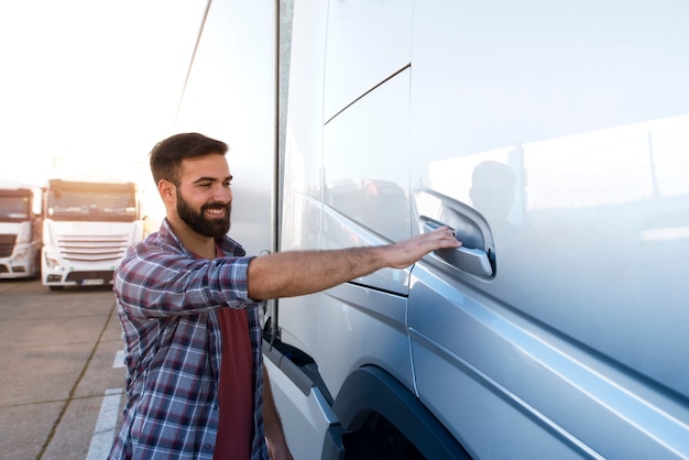 Young bearded trucker opening truck vehicle door to enter the cabin and start driving.