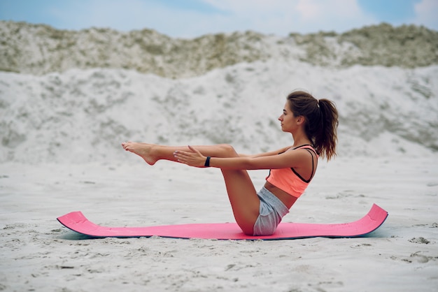 Молодые beaut практикующих йогу, делая отжимания упражнения на берегу моря.