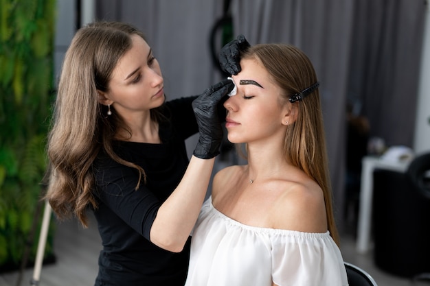 Young beautician caucasian girl holds model eyebrow correction 