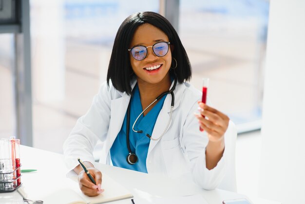 Giovane bella dottoressa afroamericana in camice bianco con uno stetoscopio.