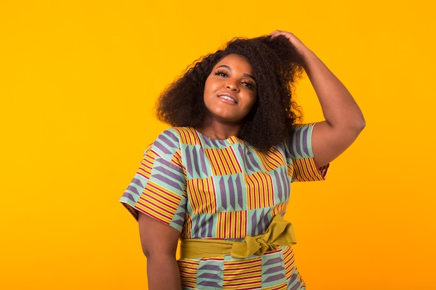 Young beautiful african american girl with an afro hairstyle. Portrait on yellow background. Girl