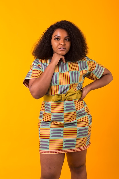 Young beautiful african american girl with an afro hairstyle. Portrait on yellow background. Girl