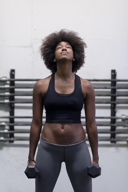 young beautiful African American woman doing bicep curls in a gym