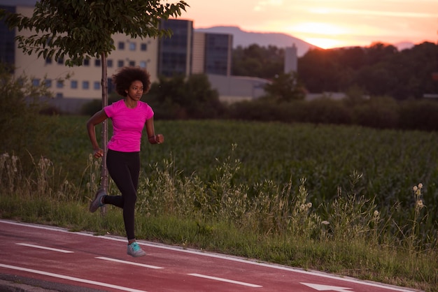 Photo young beautiful african american woman enjoys running outside beautiful summer evening in the city