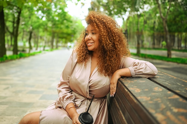 Young beautiful african american woman enjoys a walk in summer public green park a happy woman plus