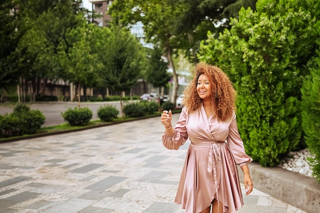 Young beautiful african american woman enjoys a walk in the summer public green park a happy woman