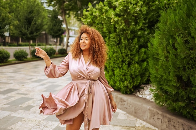 Photo young beautiful african american woman enjoys a walk in the summer public green park a happy woman